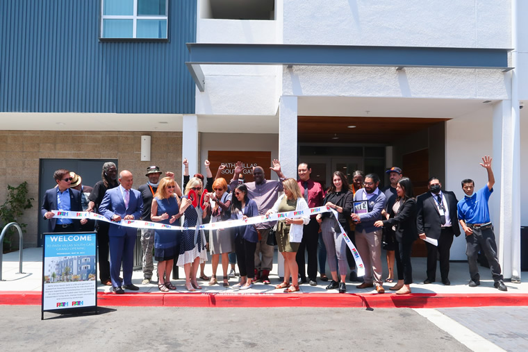 Group ribbon cutting in front of Path Villas building