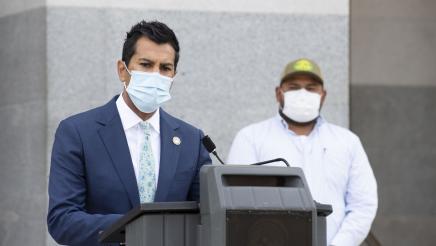 Assemblymember Robert Rivas speaking at podium with Marcos Siorda Jr. in background. 