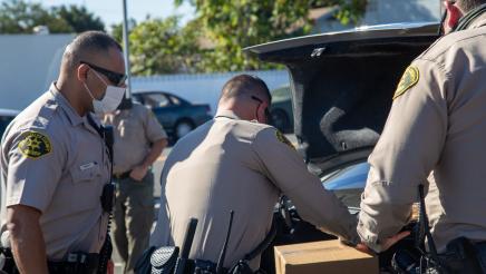 LA County Sherriffs loading food into trunk of vehicle