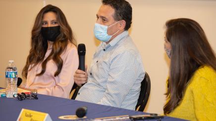 Author Ernesto Cisneros holding microphone, speaking
