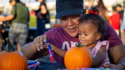 Child and parent at table, painting pumpkin