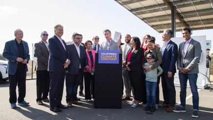Governor Newsom signs legislation while surrounded by legislators.