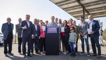Governor Newsom signs legislation while surrounded by legislators.