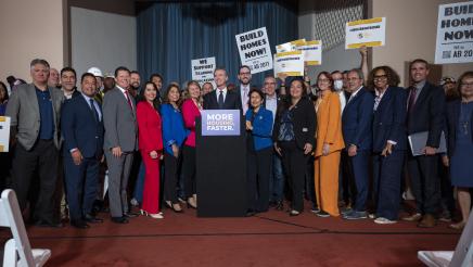 Governor Newsom signs legislation while surrounded by legislators.