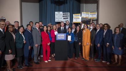 Governor Newsom signs legislation while surrounded by legislators.