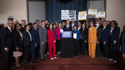 Governor Newsom signs legislation while surrounded by legislators.