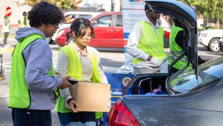 Volunteers loading food items into trunk of vehicle