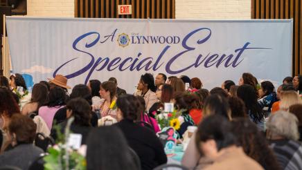 Audience in attendance with large City of Lynwood sign in background